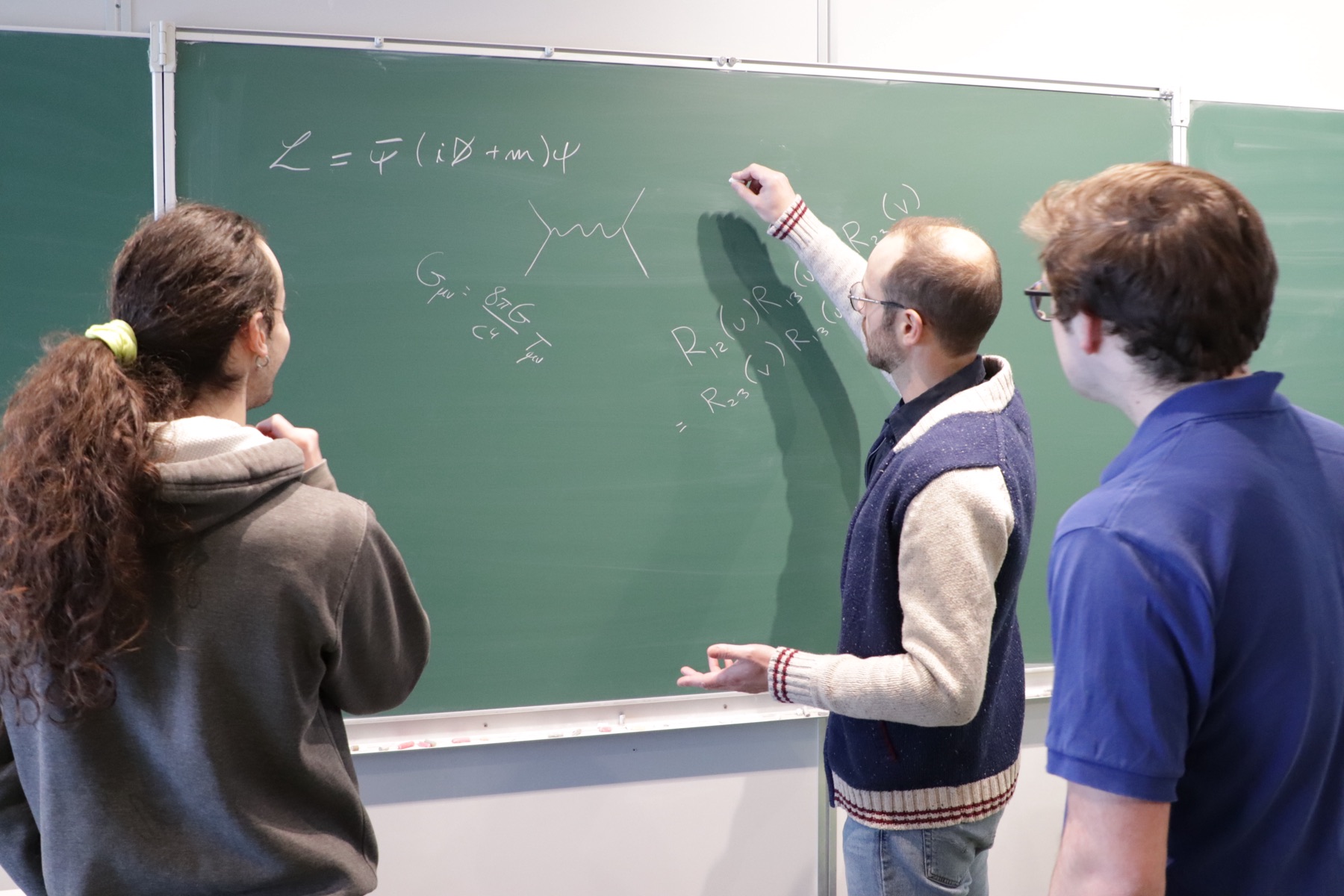 Piotr Tourkine au tableau, discutant d’équations avec deux étudiants