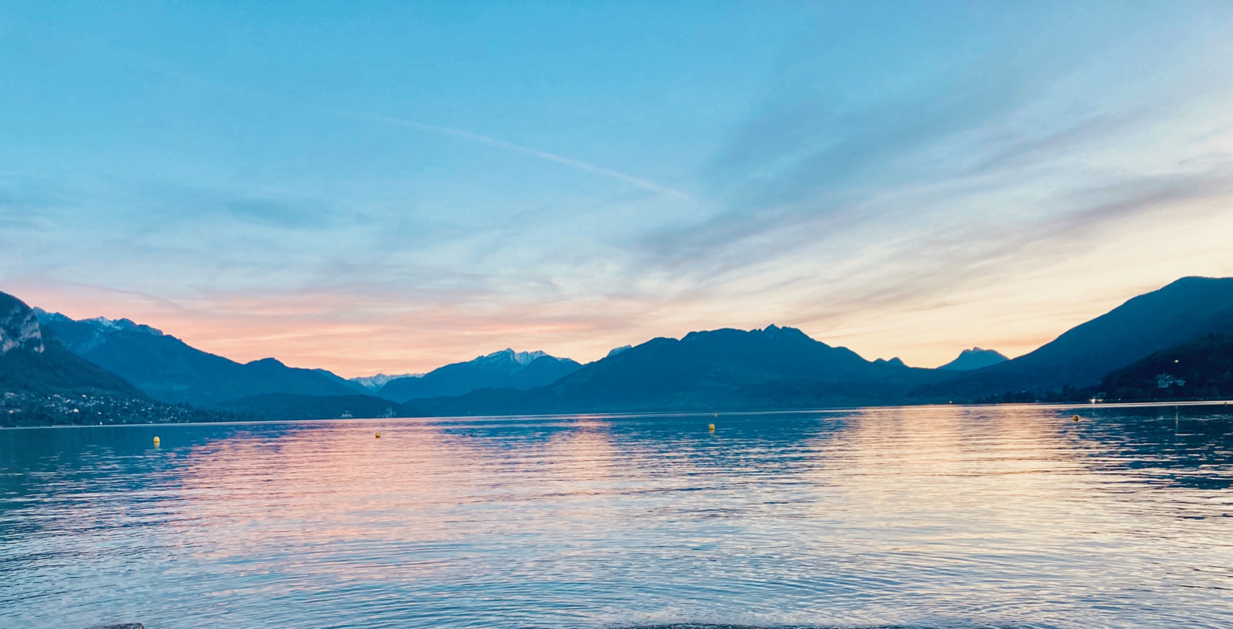 Lake Annecy at sunset, with the surrounding mountains in silhouette